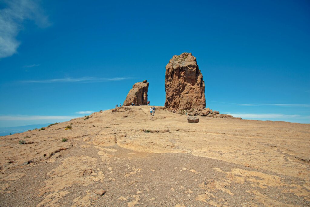 Woman Standing on Brown Mountain Under Blue Sky